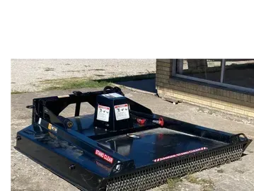 Black rotary brush cutter attached to a tractor, on a concrete surface.