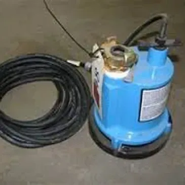 Blue submersible pump with coiled black power cord on a concrete surface.