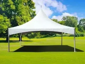 White high-peak tent in a grassy area, under a blue sky with trees.
