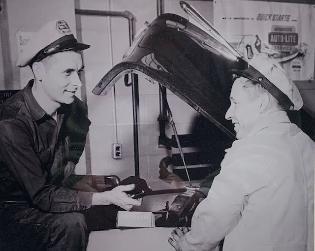 A black and white photo of two men working on a car