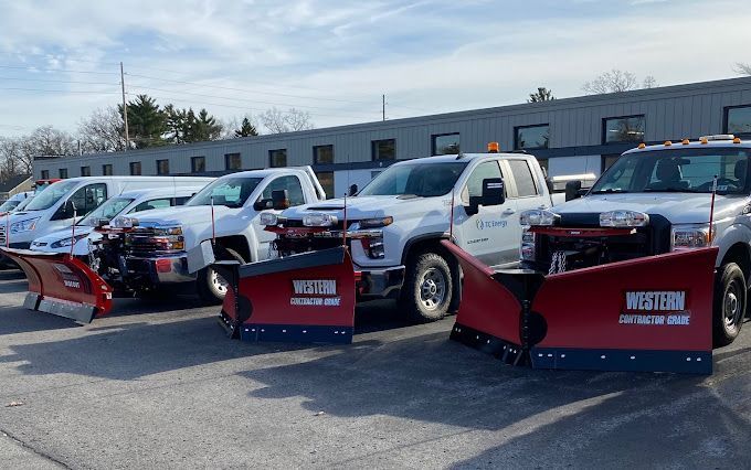 A row of snow plows are parked in front of a building.
