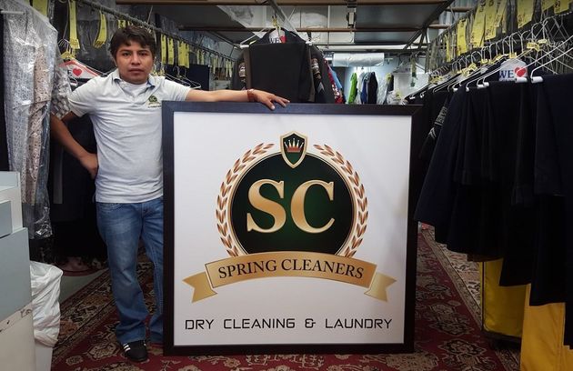 Person in a lime green jacket reaching between rows of hanging clothes in a clothing storage area