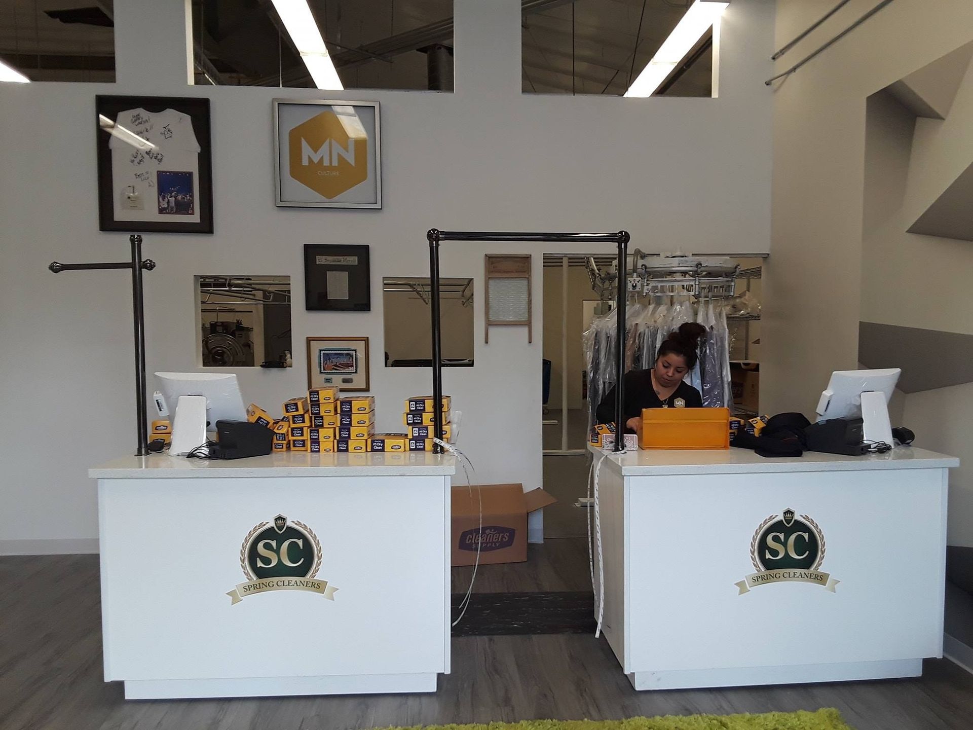Booth display with white counters, SC logos, and a person standing behind the right counter.