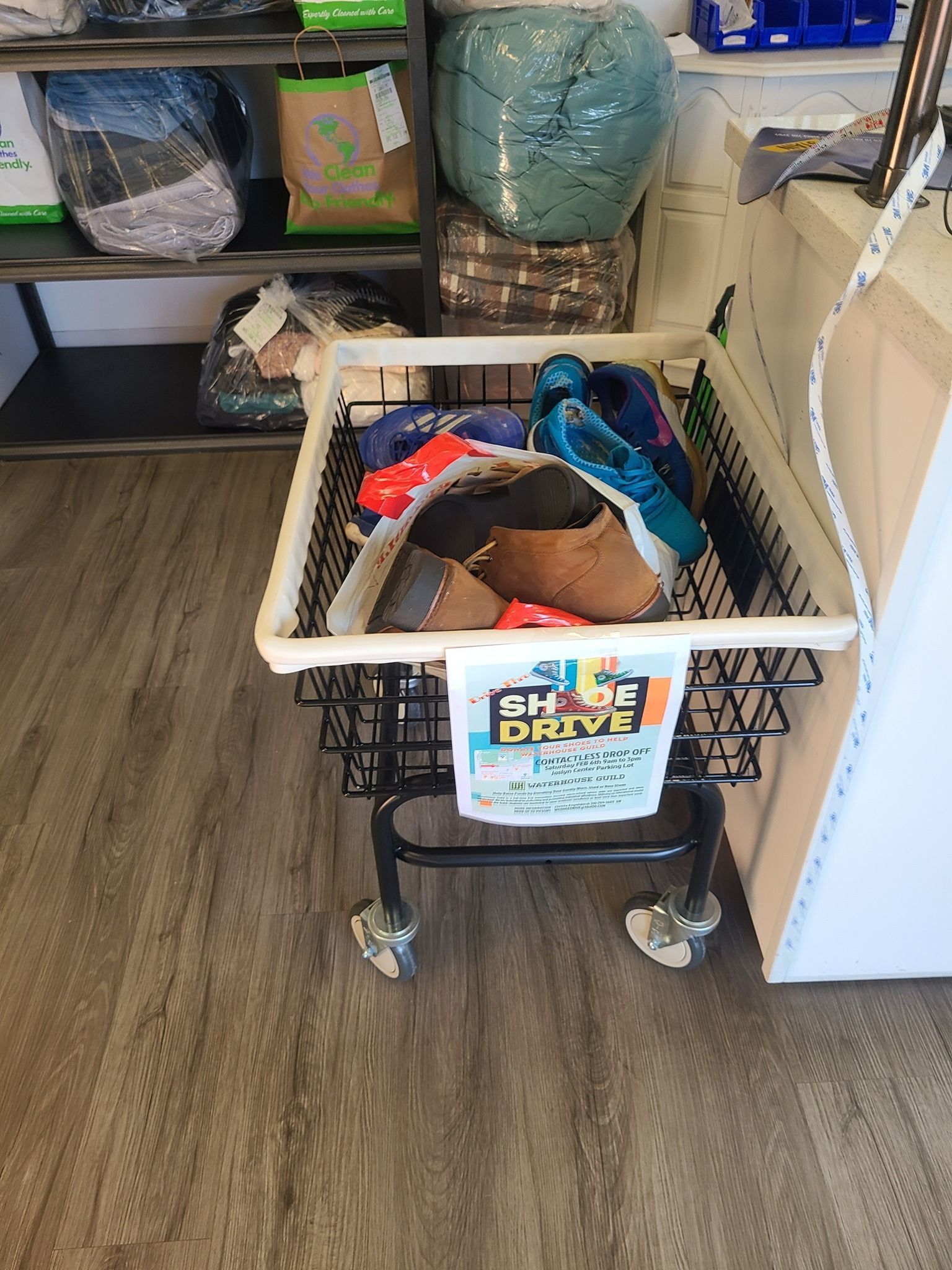 Shopping cart filled with assorted items in a store aisle, with a sign on the front.