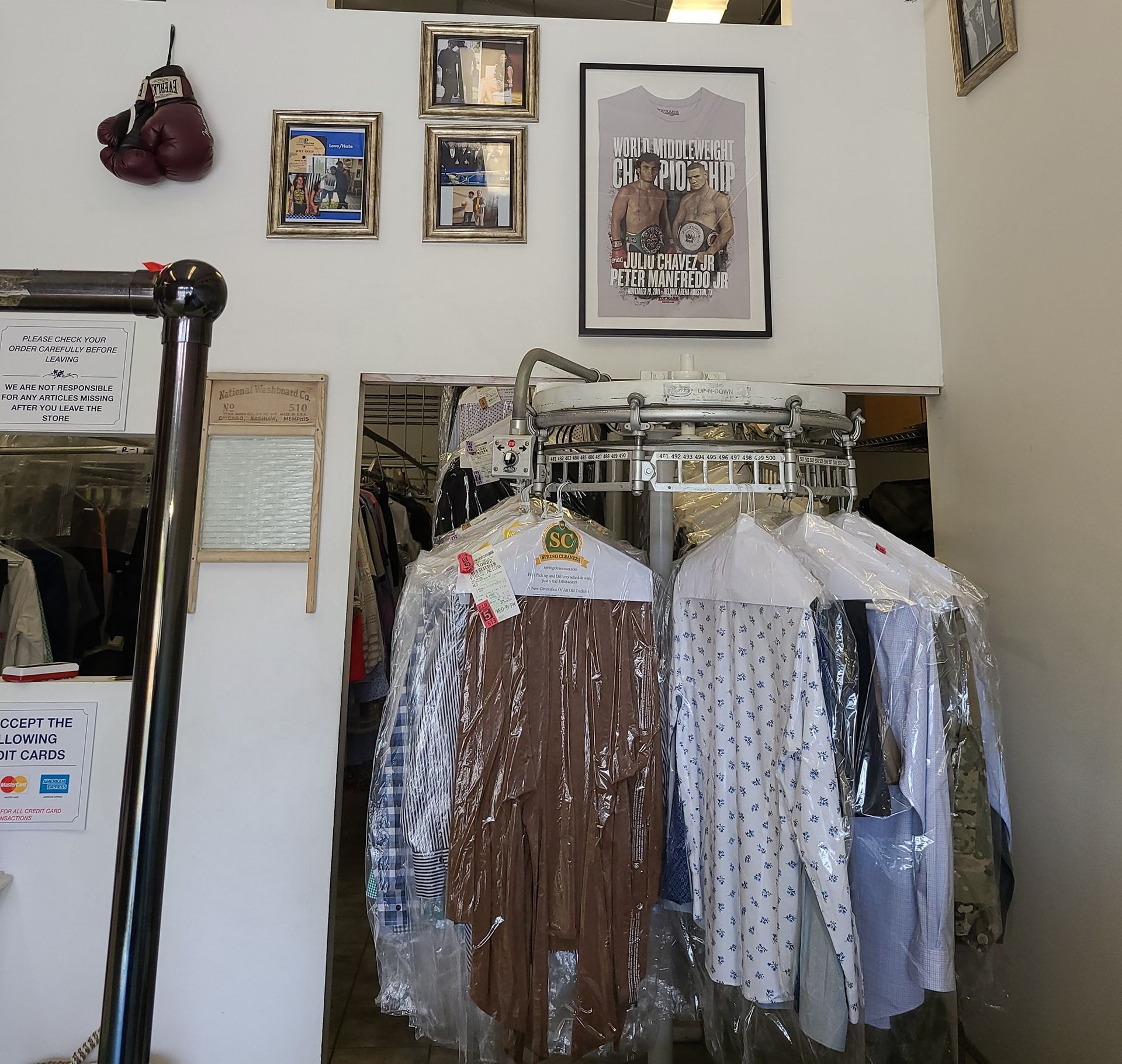 Clothing rack with hanging shirts in a small room, beneath framed wall art and photos.