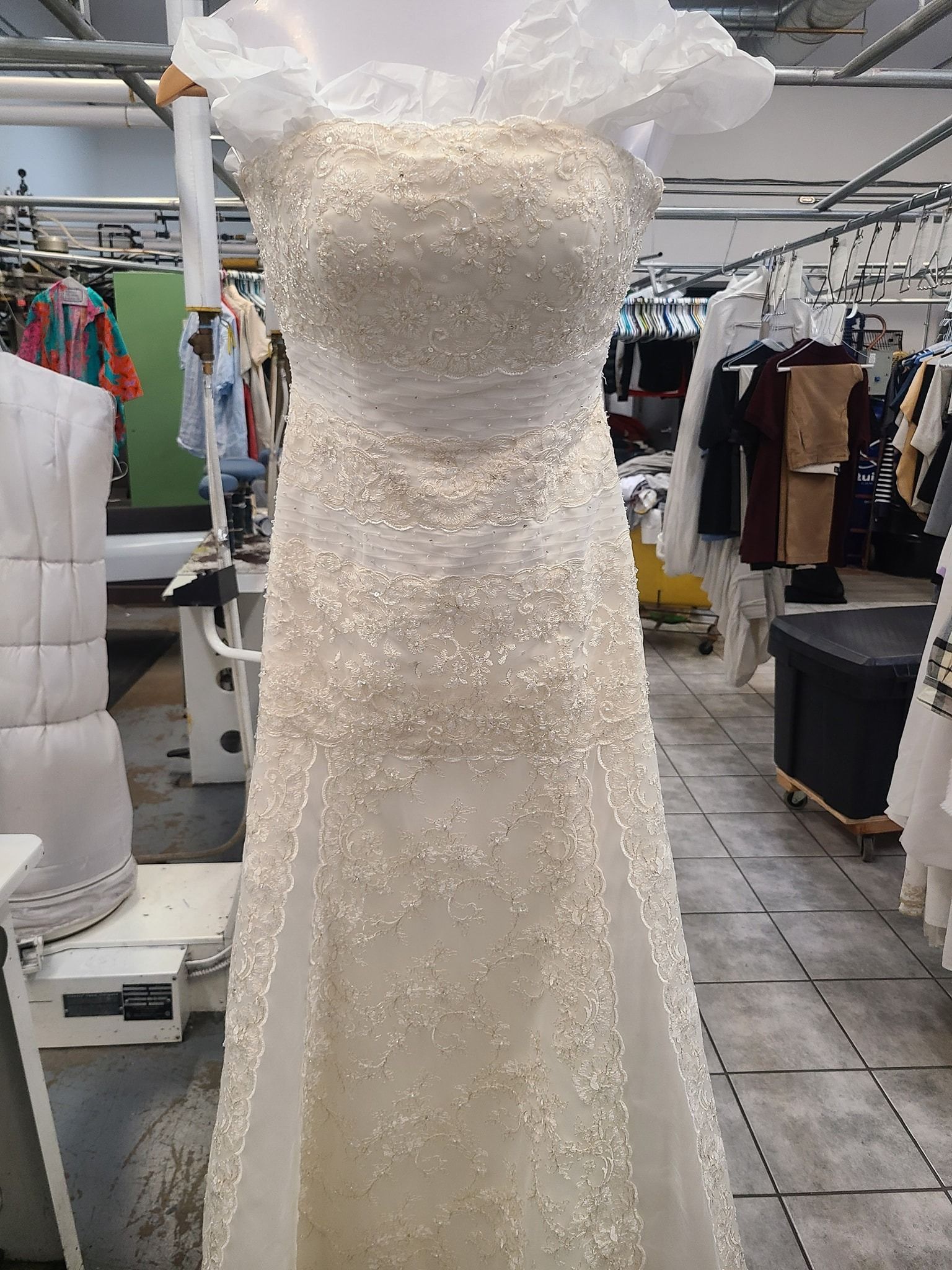 White sequined strapless wedding dress on a mannequin in a clothing workshop