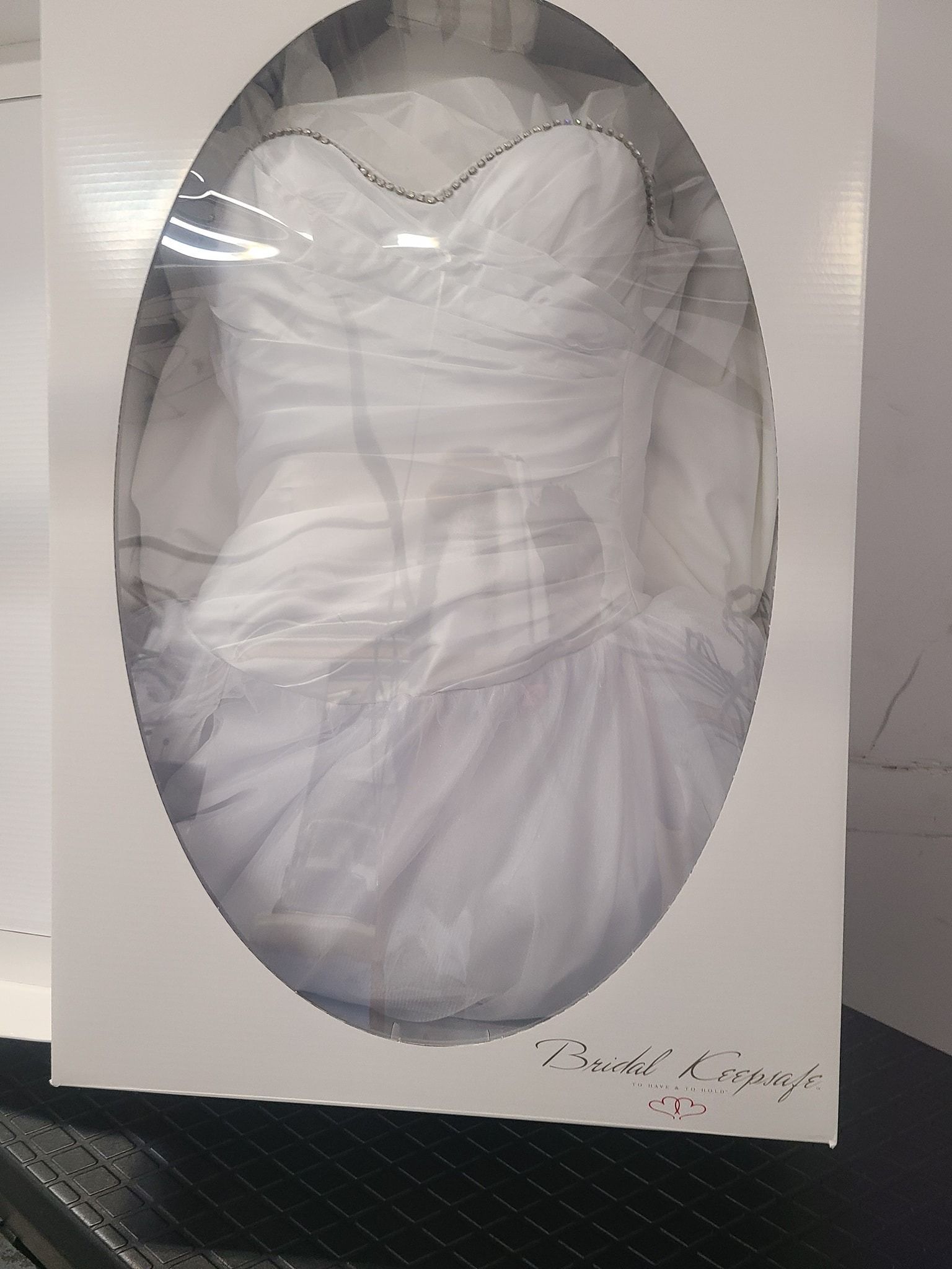 Oval-shaped white dress with sheer sleeves, displayed on a hanger against a white background.