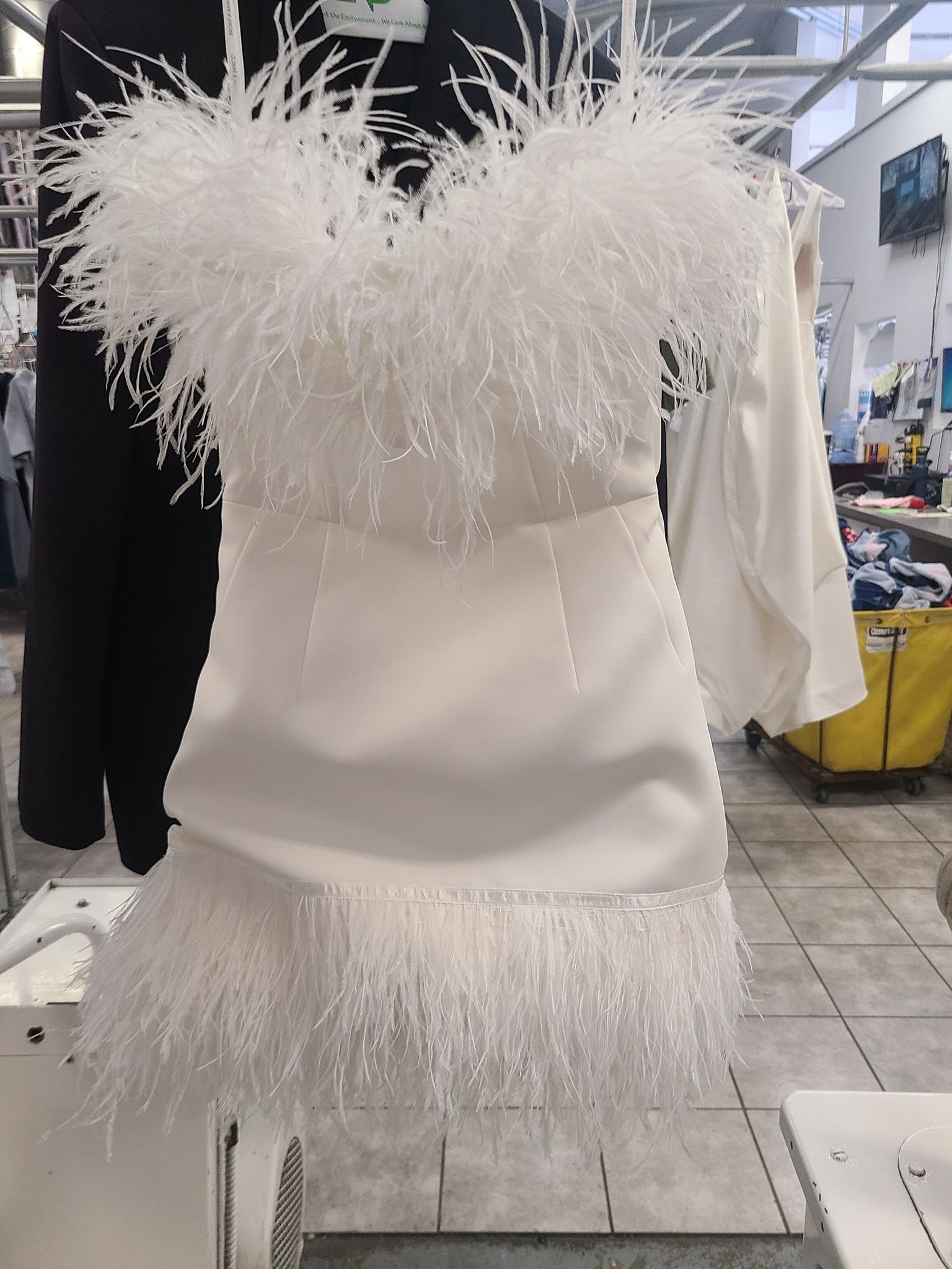White feather-trimmed dress on display in a clothing store