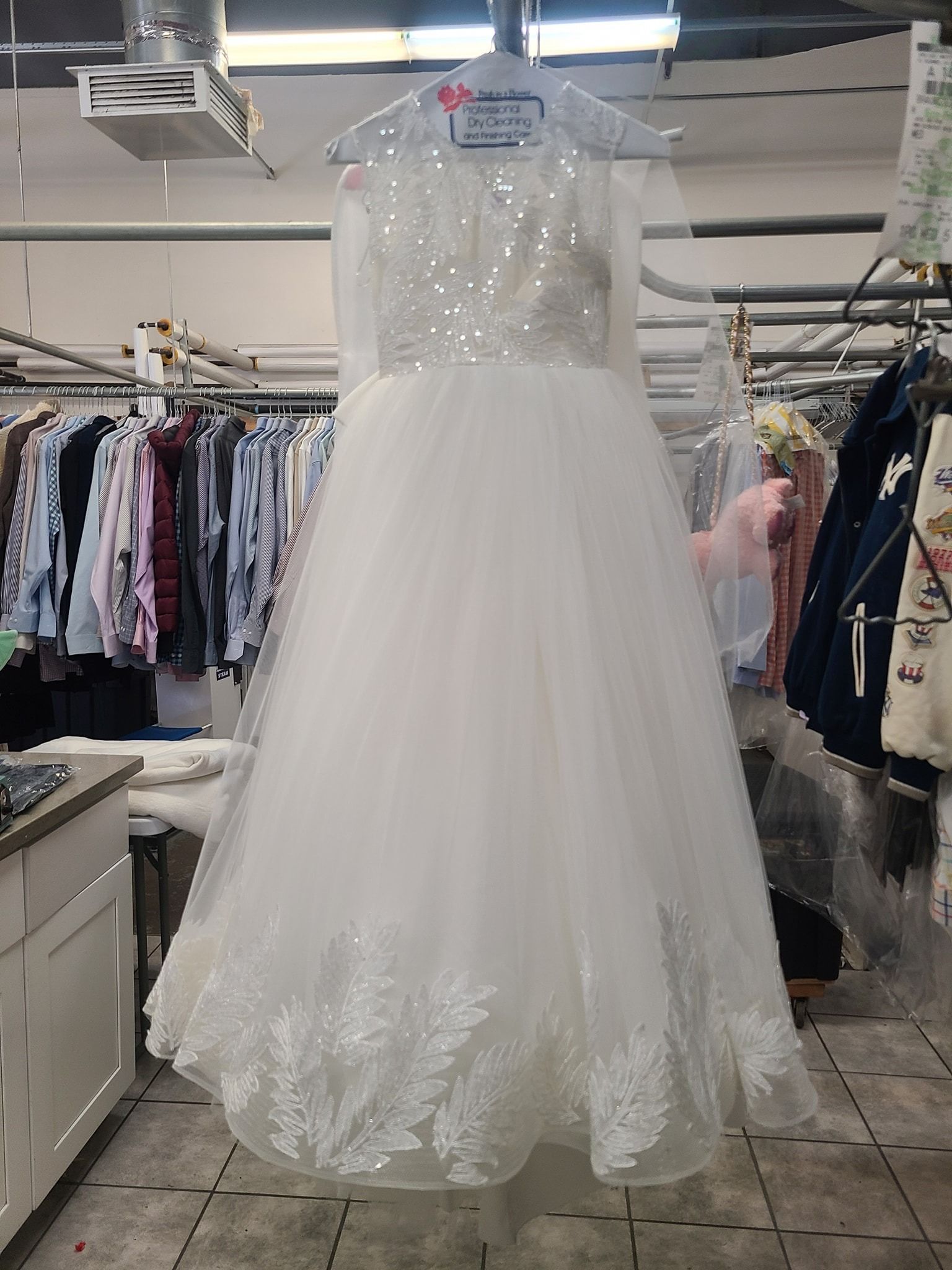 White sequined sleeveless dress with tulle skirt hanging in a clothing store aisle