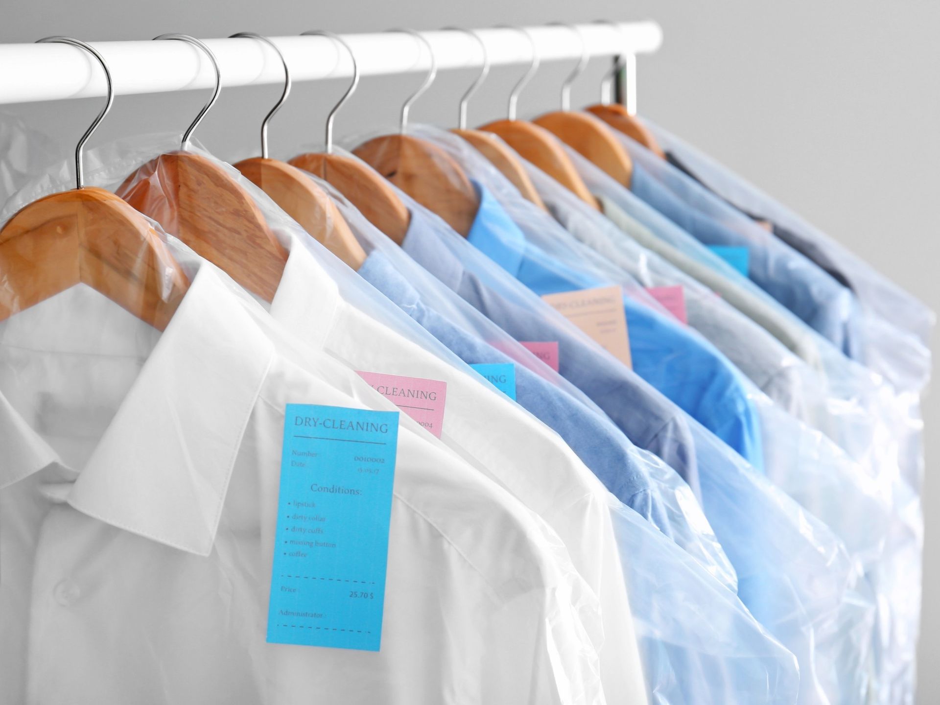 Row of white shirts on wooden hangers with blue price tags hanging on a rack