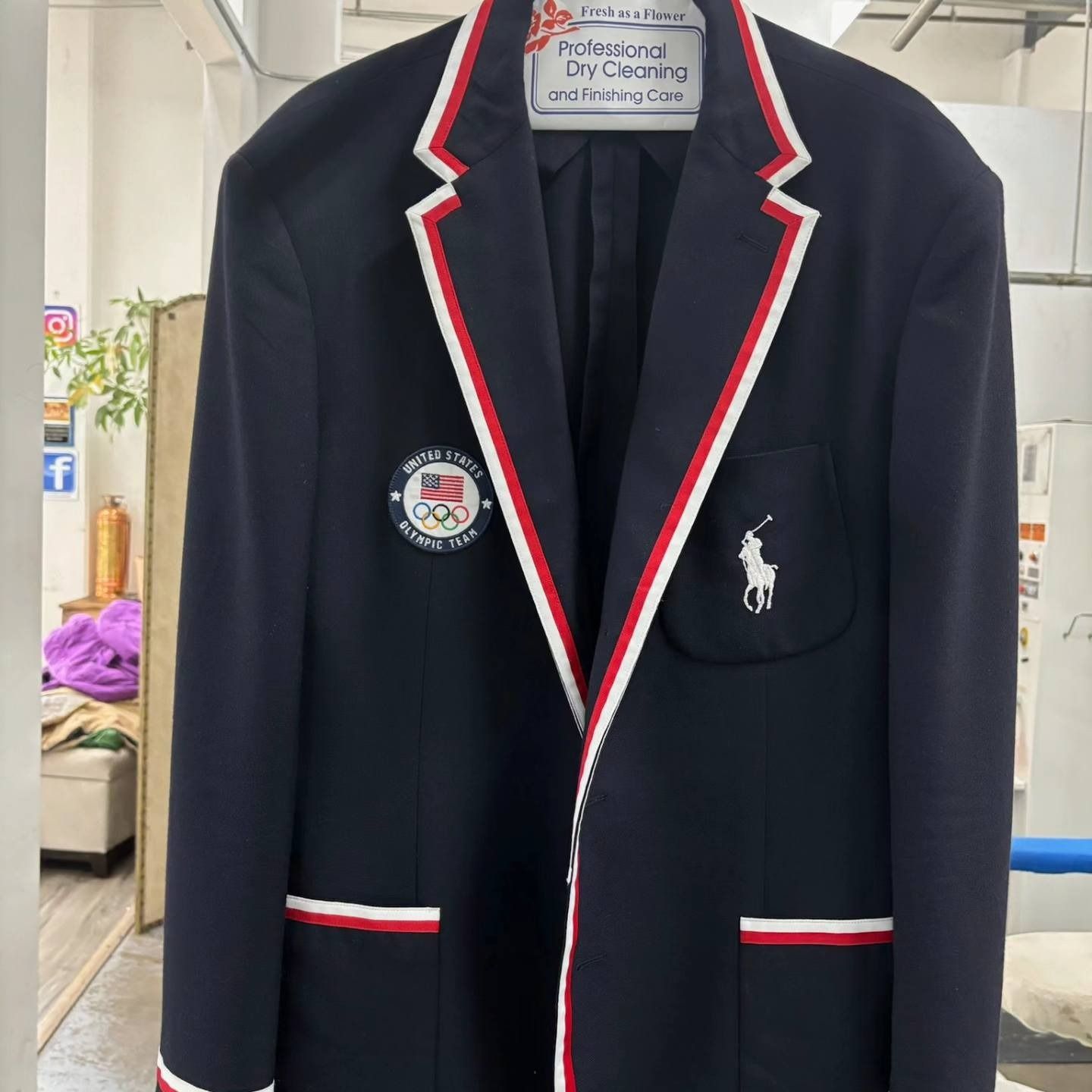 Navy blazer with red-and-white trim hanging on a hanger indoors