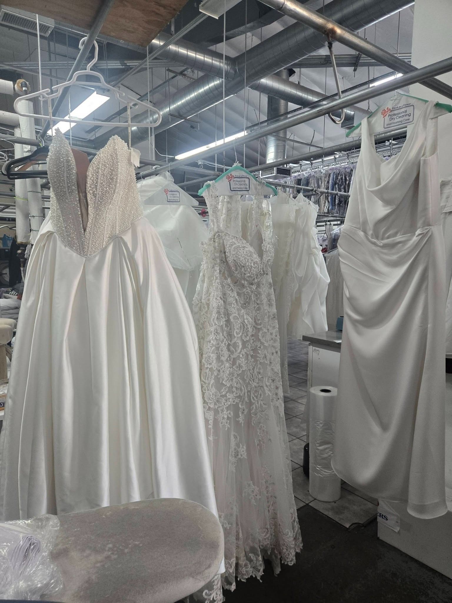 Wedding dresses hanging in a bridal shop warehouse with rows of gowns and overhead lighting