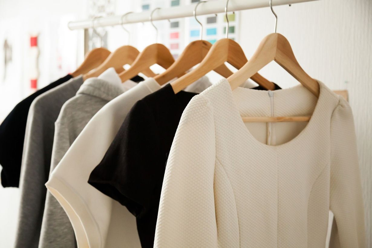 Assorted sweaters on wooden hangers hanging on a clothing rack