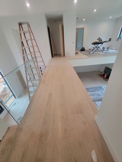 A ladder is sitting on top of a wooden floor in a room.