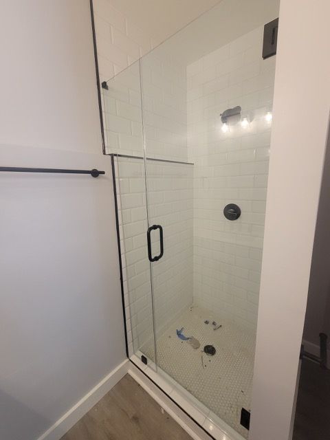 A bathroom with a walk in shower with a clear glass door.