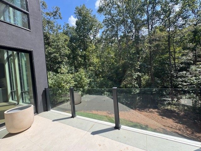 Modern home with a glass-paneled balcony overlooking trees