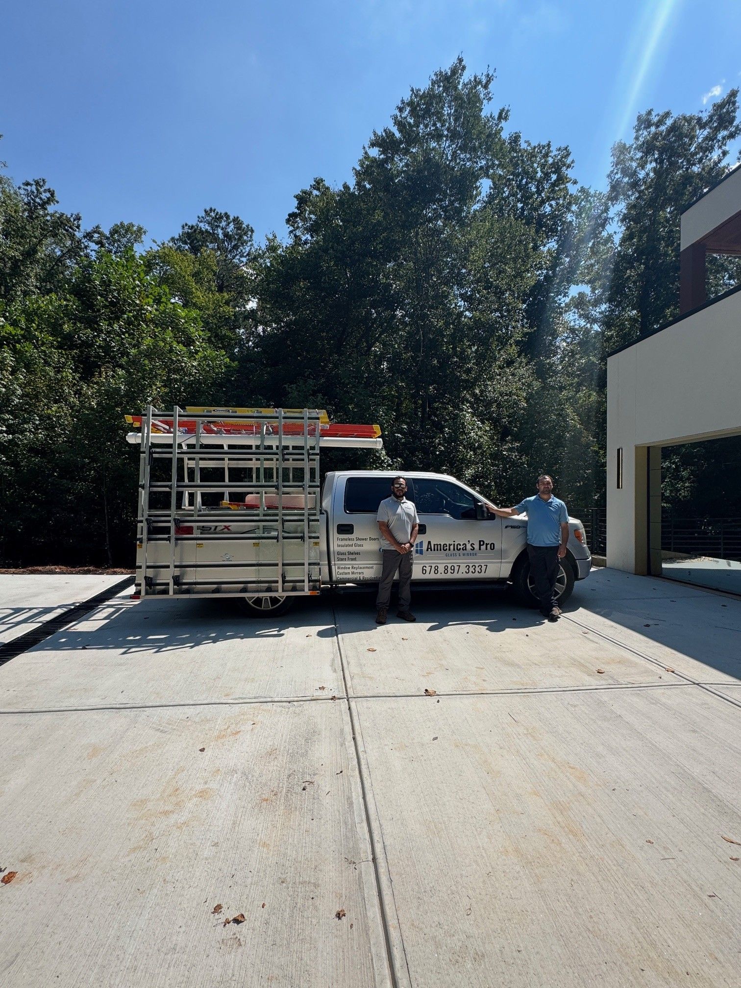 Two men are standing in front of America's Pro Glass and Mirror LLC's truck