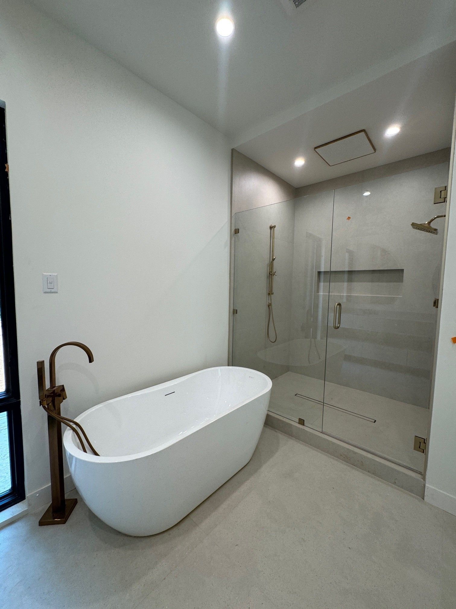 Modern bathroom with a white soaking tub, glass shower, and bronze fixtures