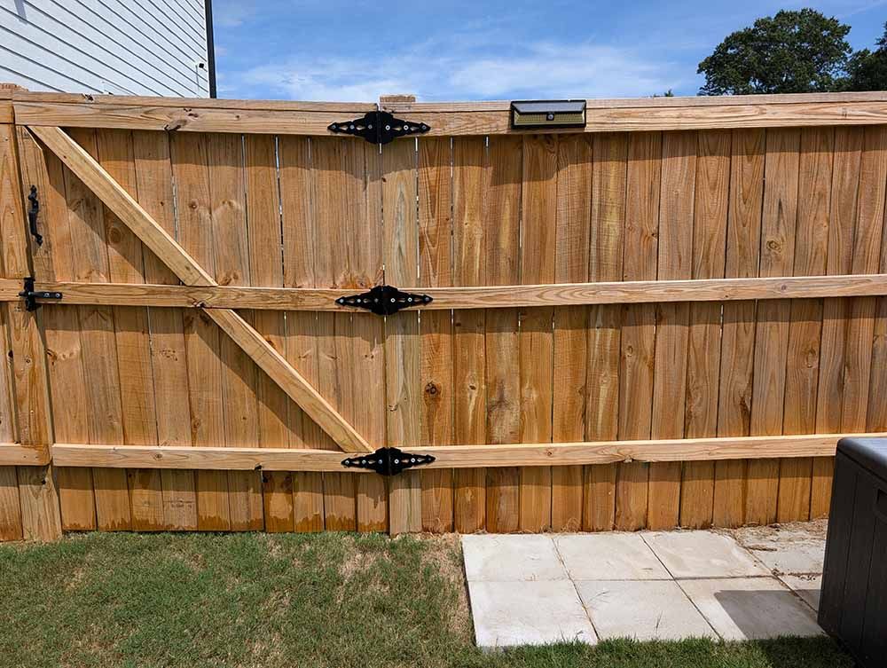 A wooden fence with a gate in the backyard of a house.