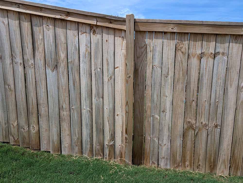 A wooden fence is sitting on top of a lush green field.