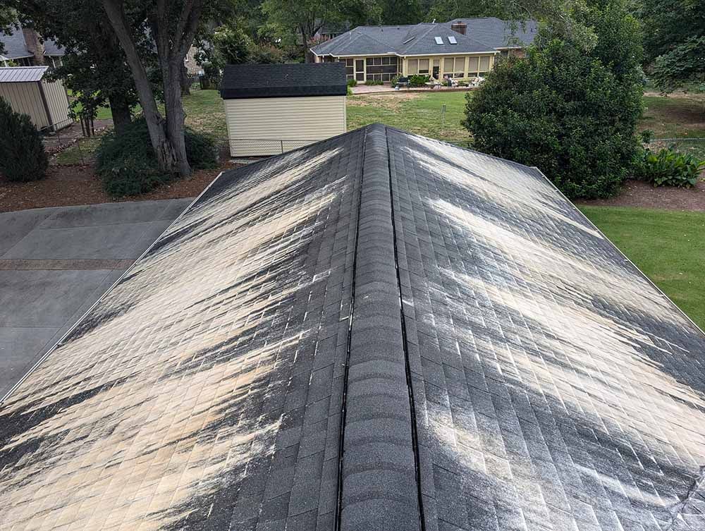 A roof with a lot of dust on it and a house in the background.