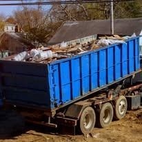Blue dumpster overflowing with debris on a trailer, outdoors.