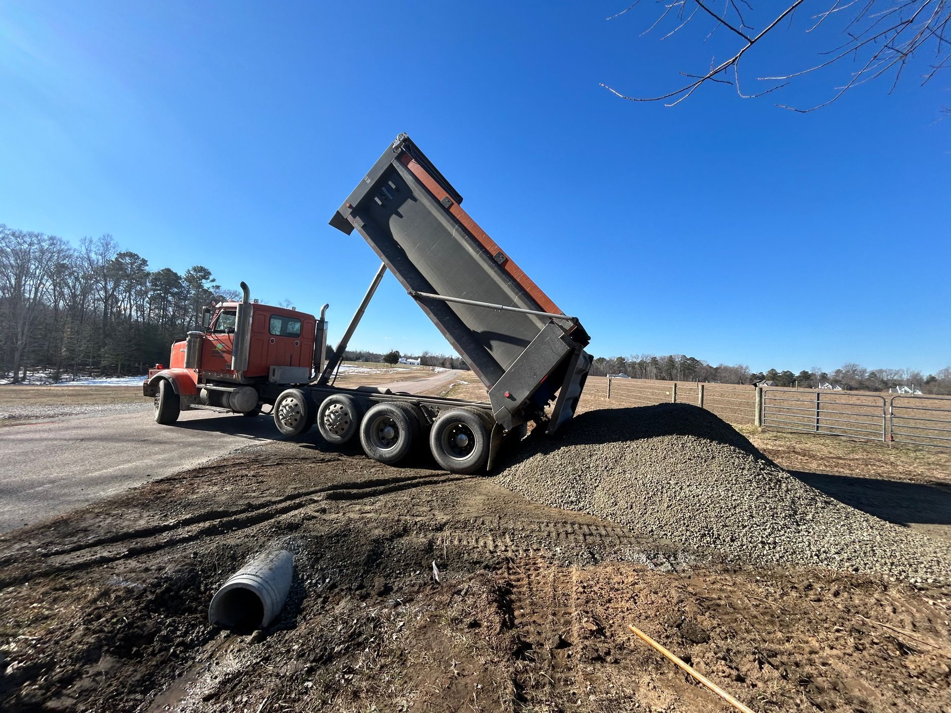 A dump truck is being loaded with gravel on the side of the road.