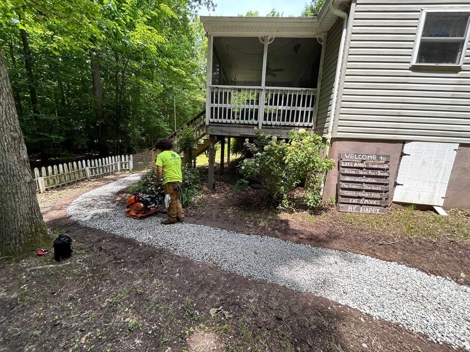A man is standing on a gravel path in front of a house.