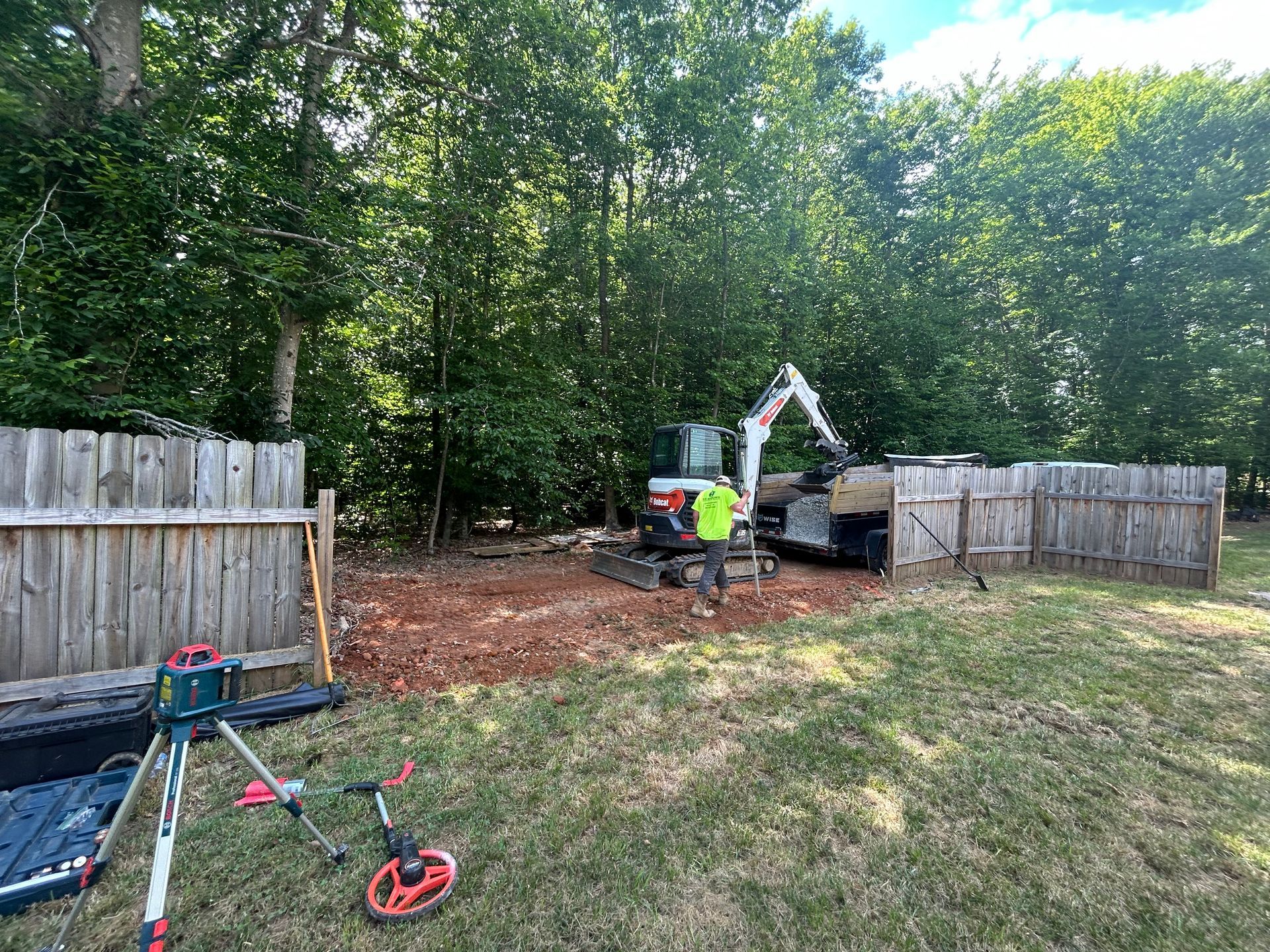 A man is standing in a yard with a bulldozer in the background.