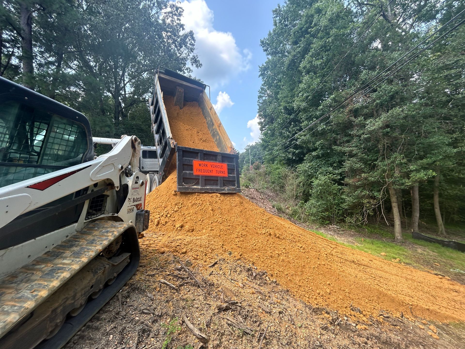 A bulldozer is dumping dirt into a dumpster.