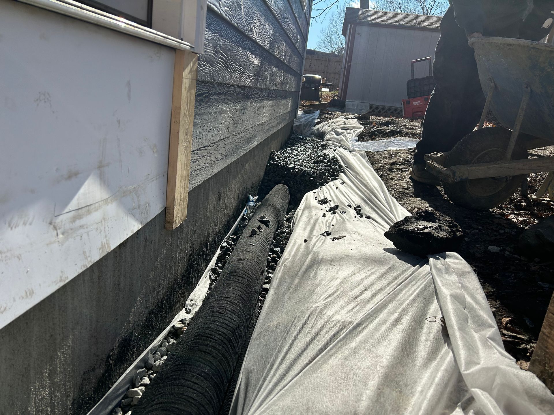 A drainage system is being installed on the side of a house.