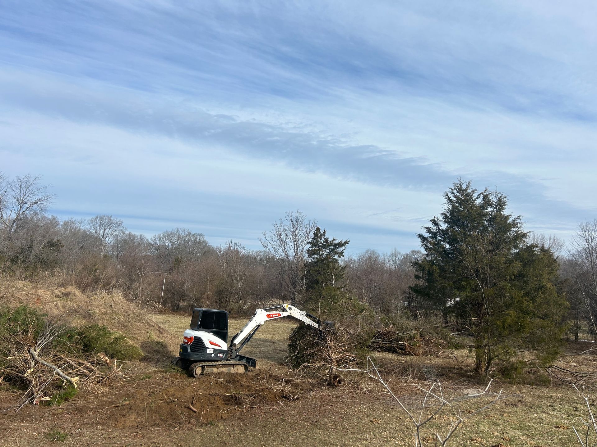 A small excavator is digging a hole in the middle of a field.
