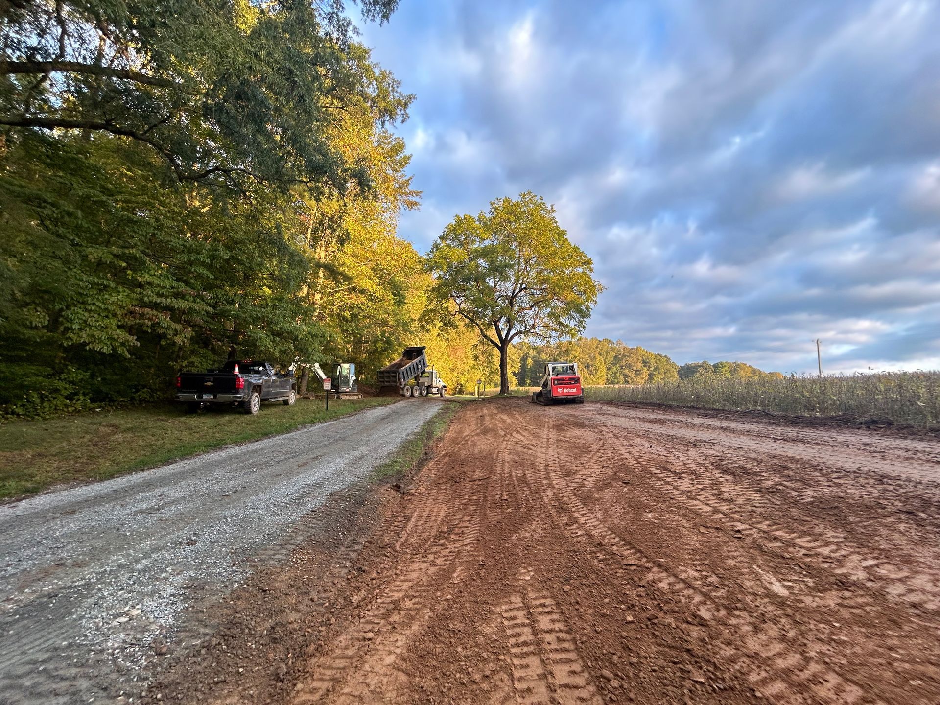 A dirt road with cars parked on the side of it.