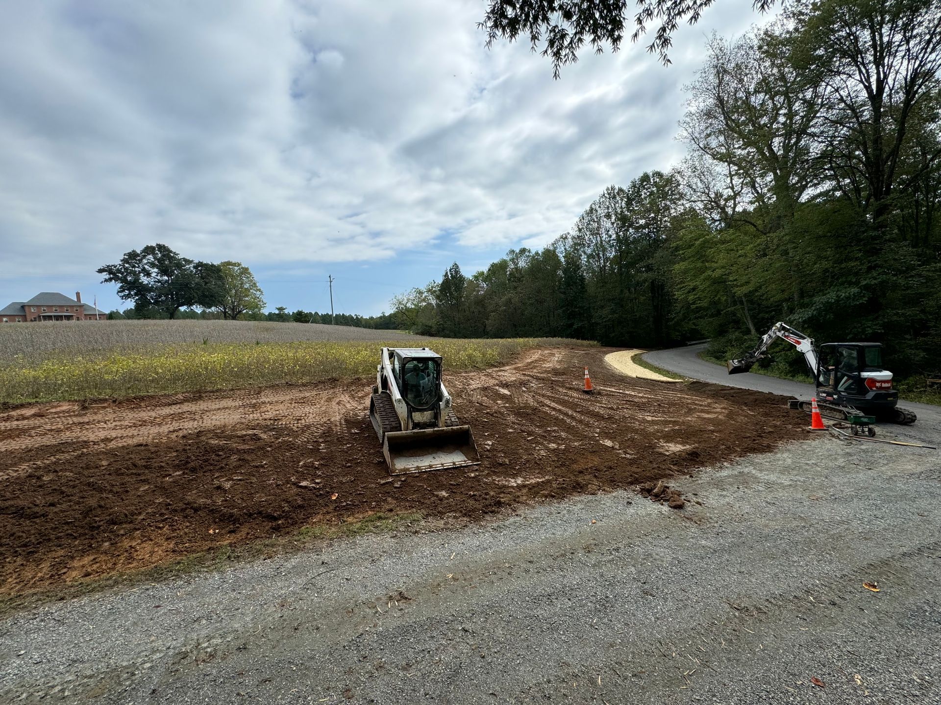 A bulldozer is working on a gravel road in a field.