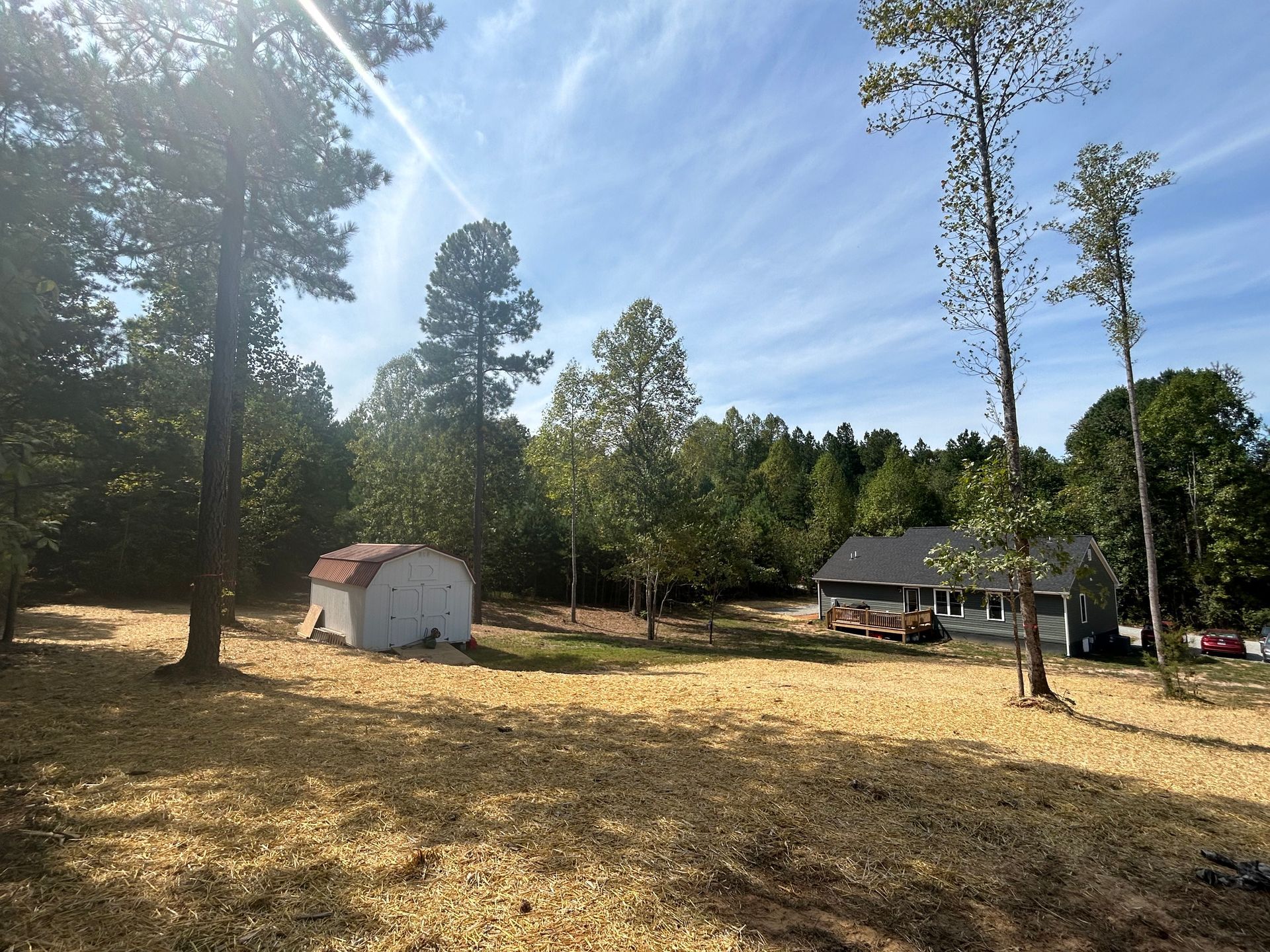 A house is sitting in the middle of a field surrounded by trees.