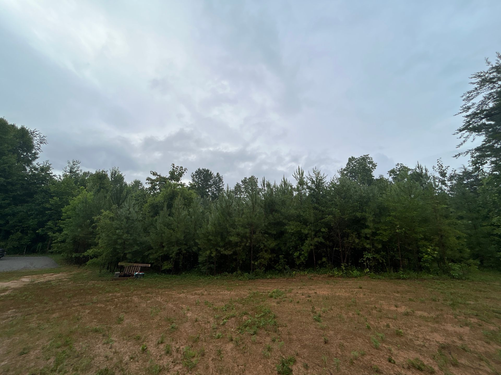 There is a picnic table in the middle of a field surrounded by trees.