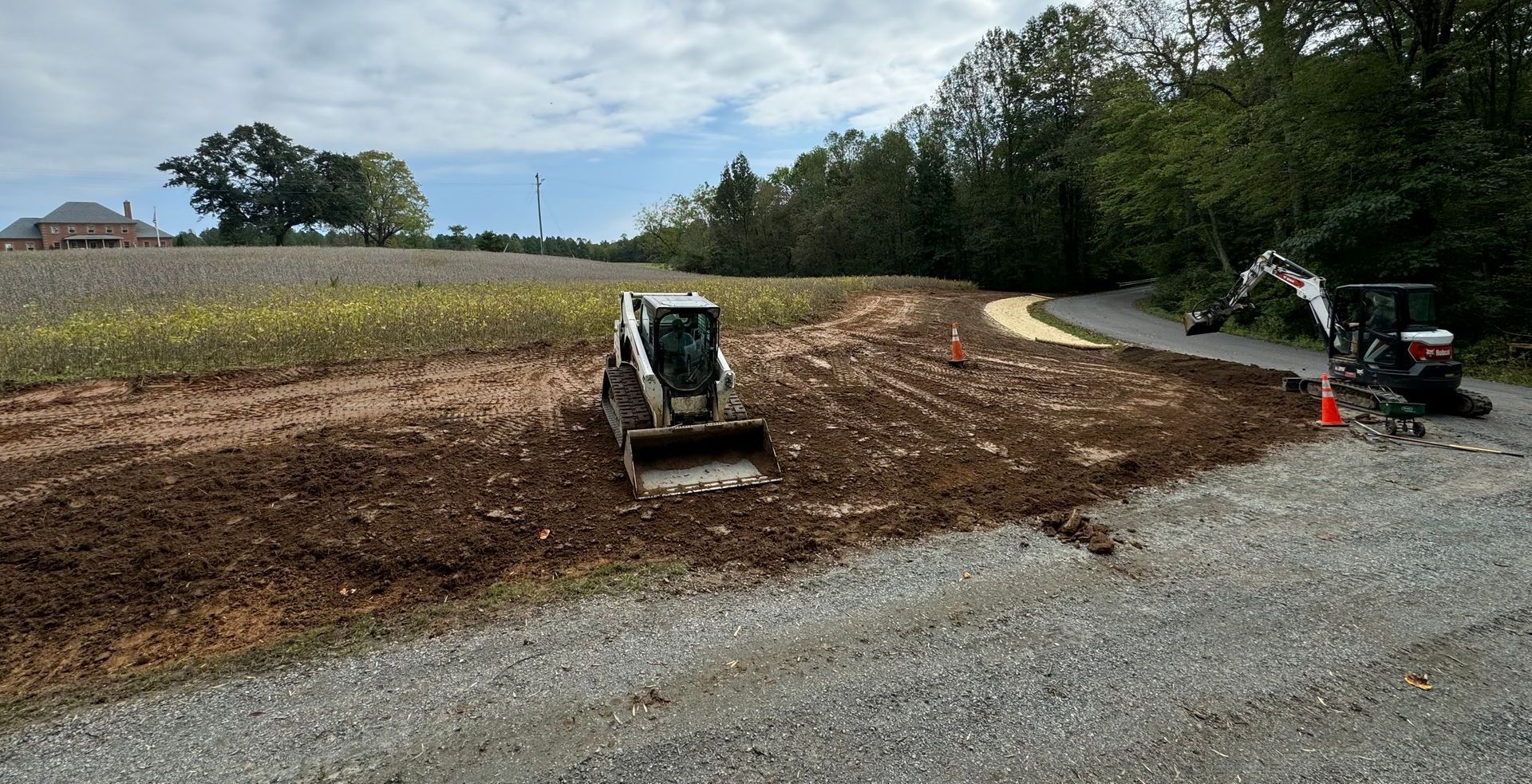 A bulldozer and an excavator are working on a gravel road.