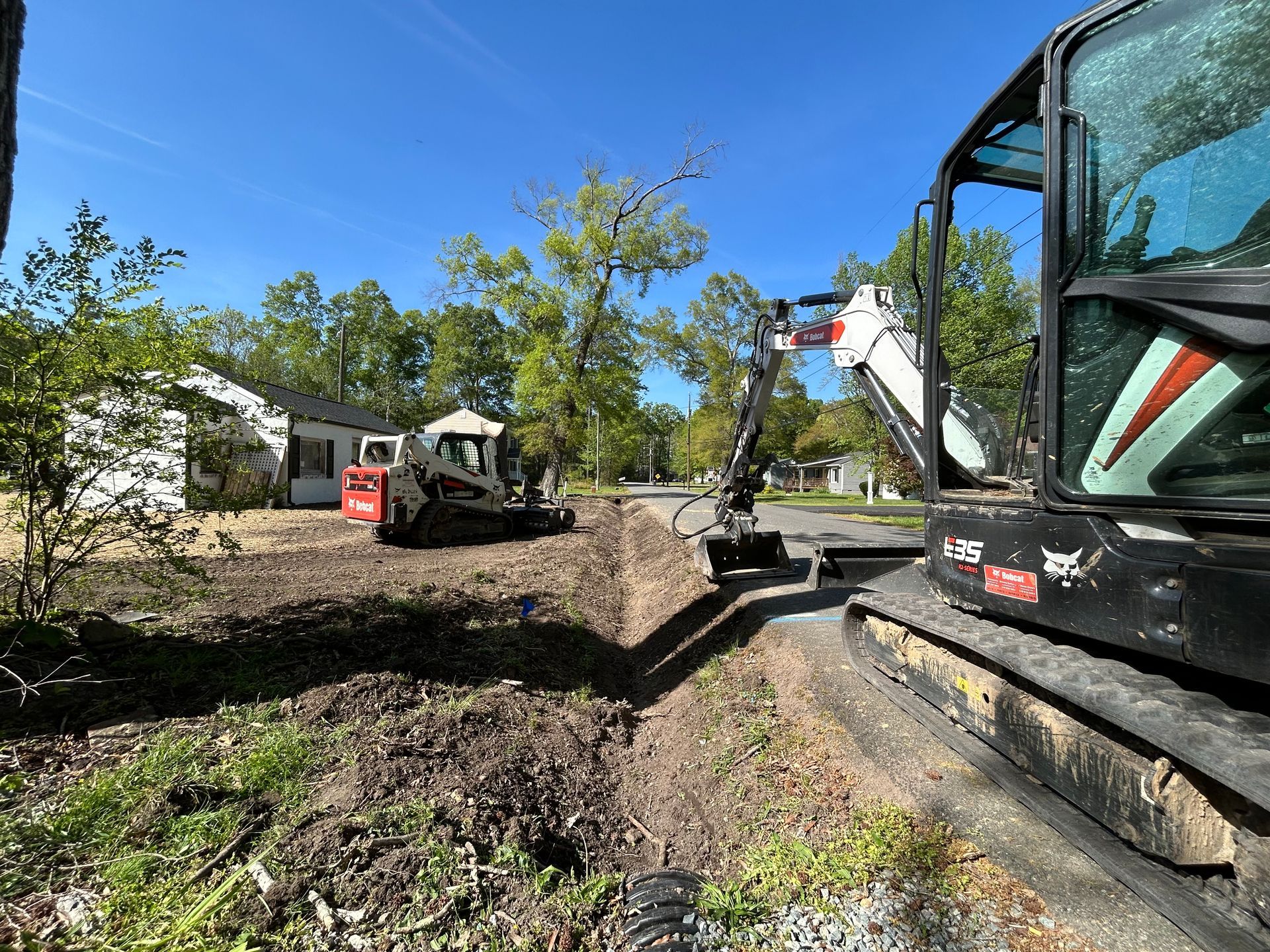 A bulldozer is digging a hole in the ground in front of a house.