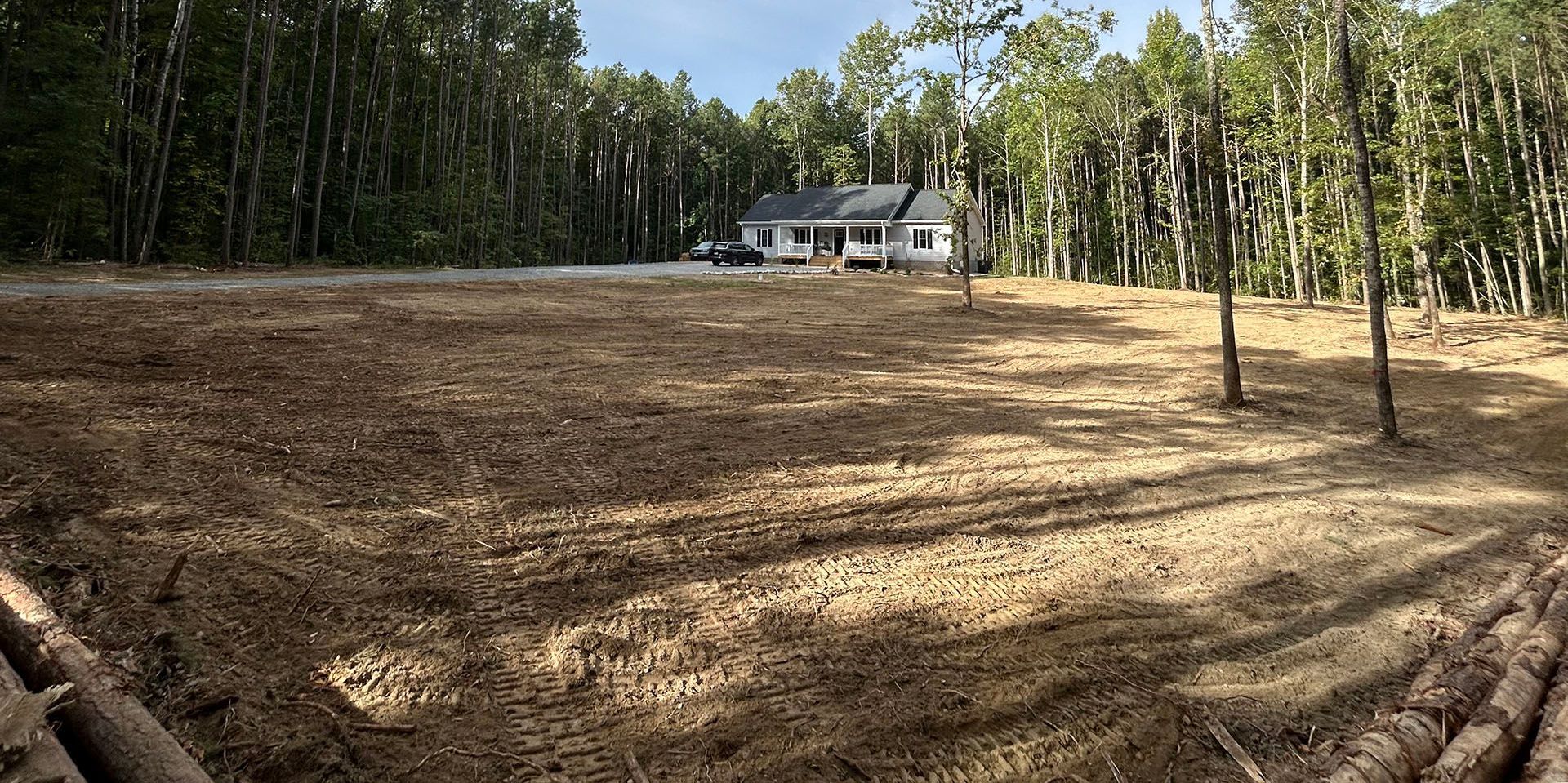 A house is sitting in the middle of a field surrounded by trees.