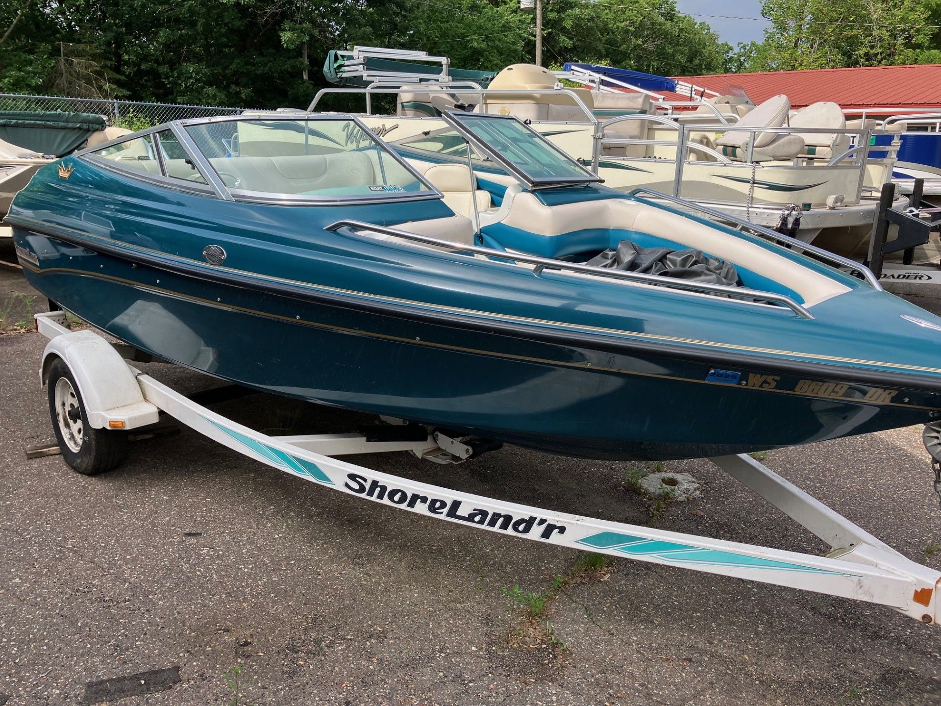 A blue boat is parked on a trailer in front of a building.
