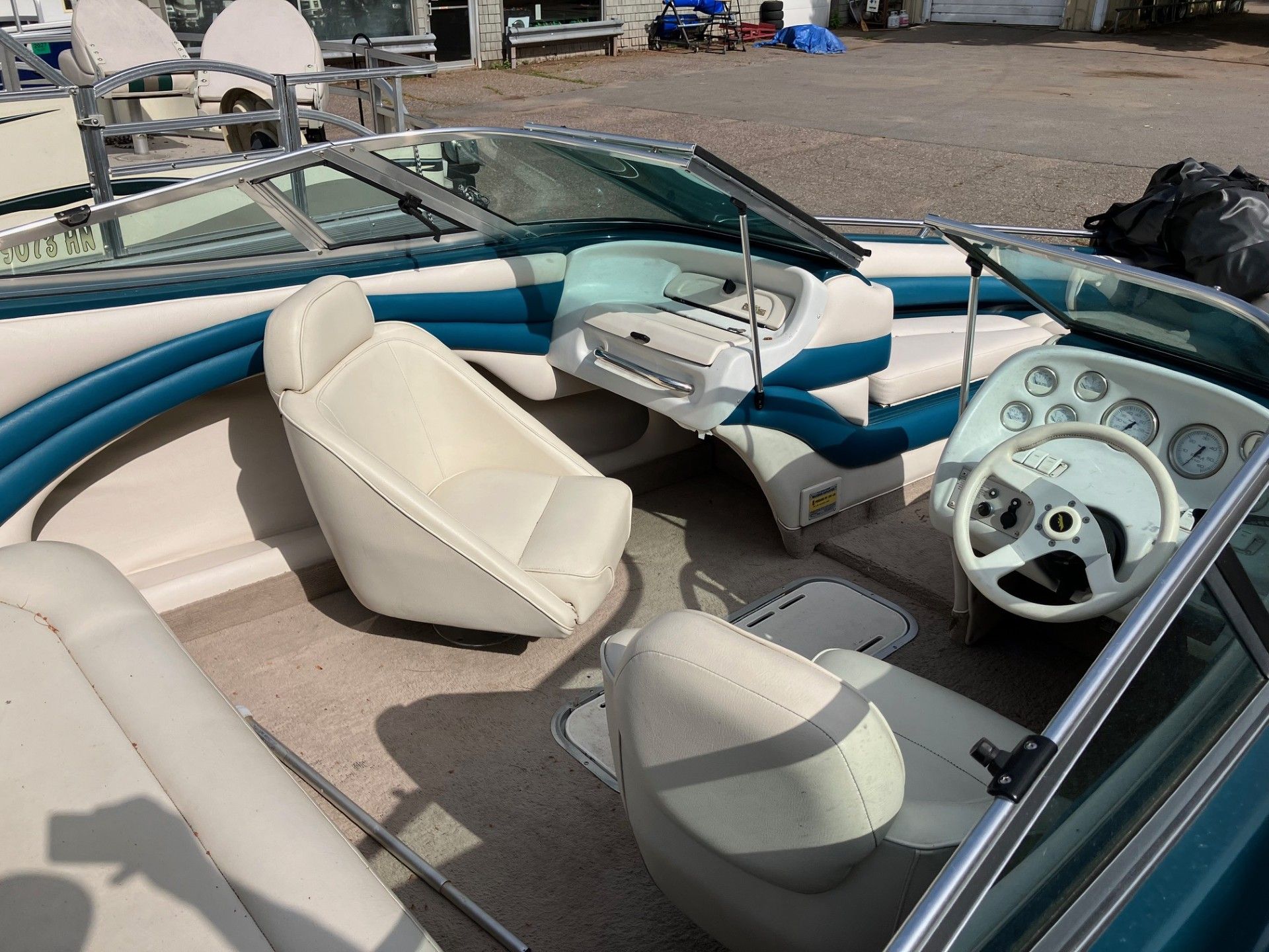 The inside of a boat with white seats and a steering wheel