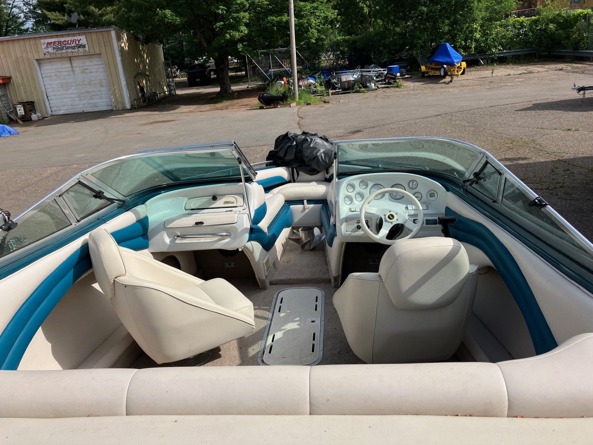 A boat is parked in a parking lot in front of a garage.