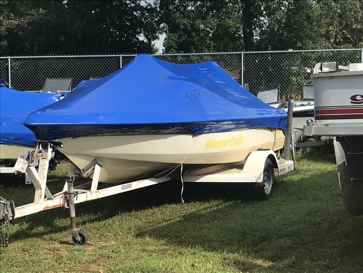 A boat on a trailer is covered in a blue tarp.