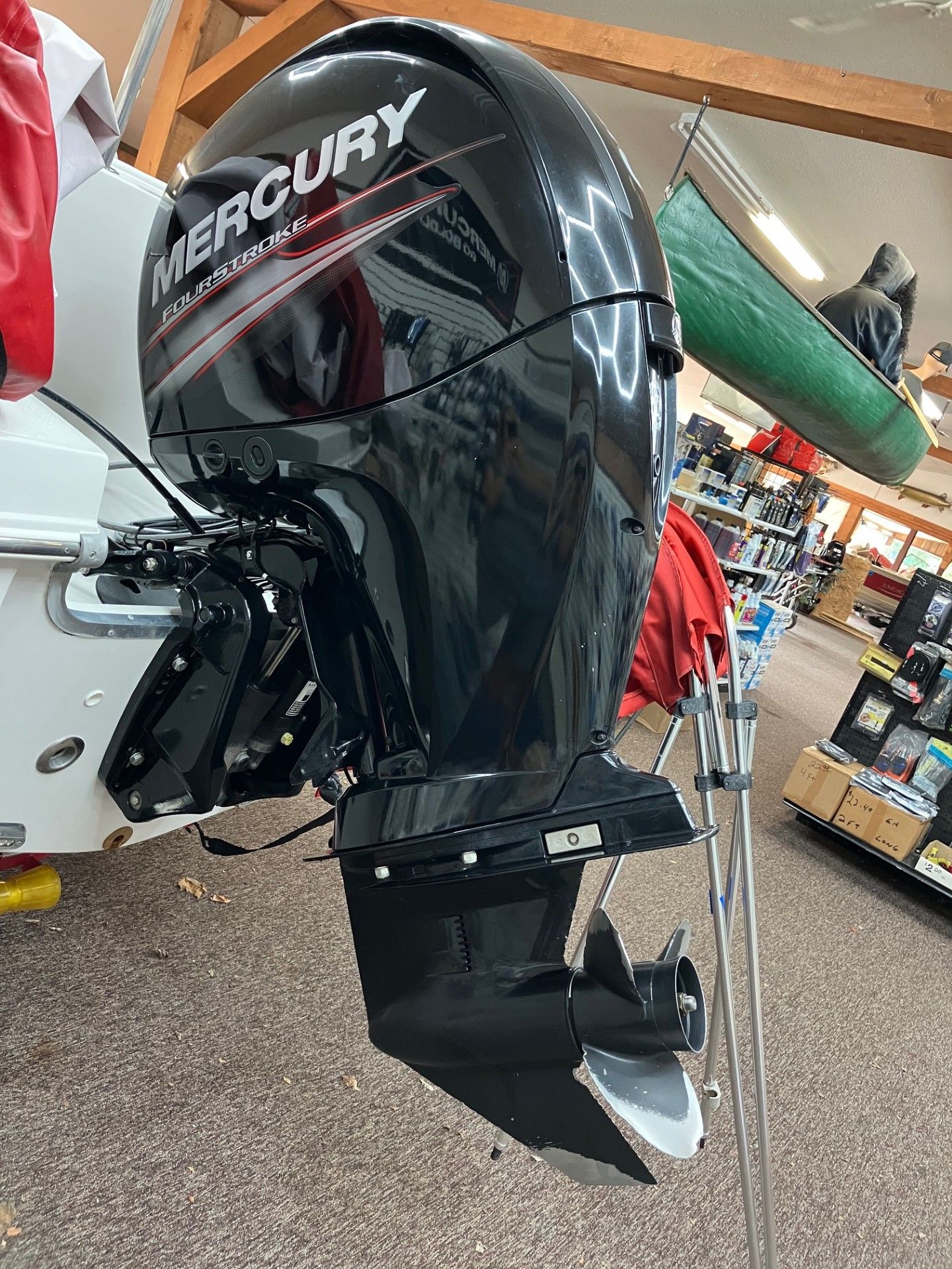 Black Mercury outboard motor mounted on a boat, shown indoors in a store.