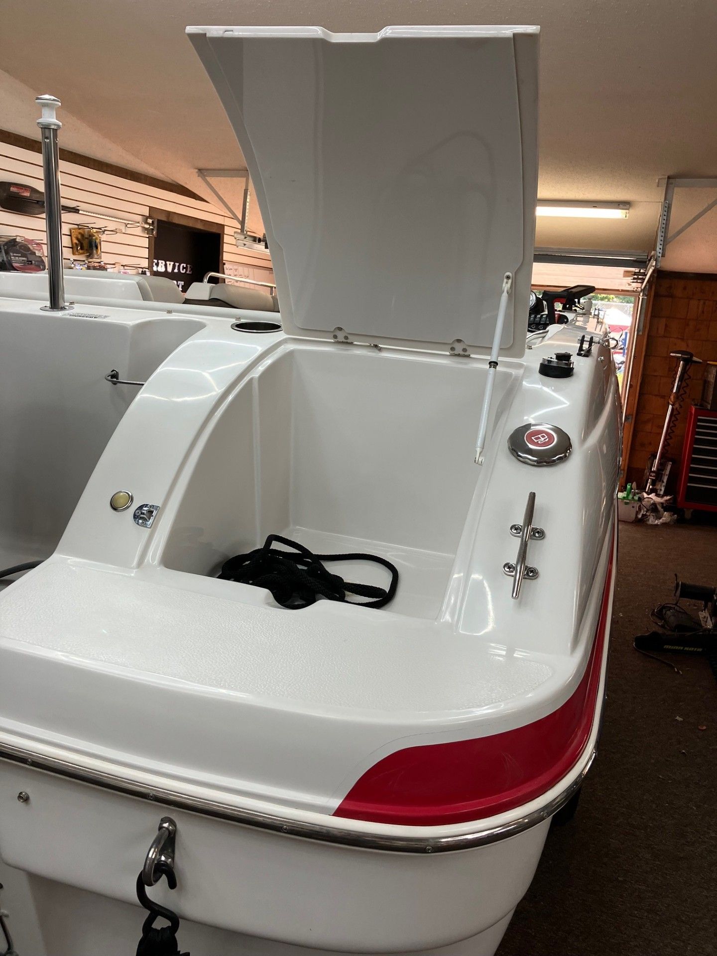 White motorboat with open storage hatch inside a garage or showroom