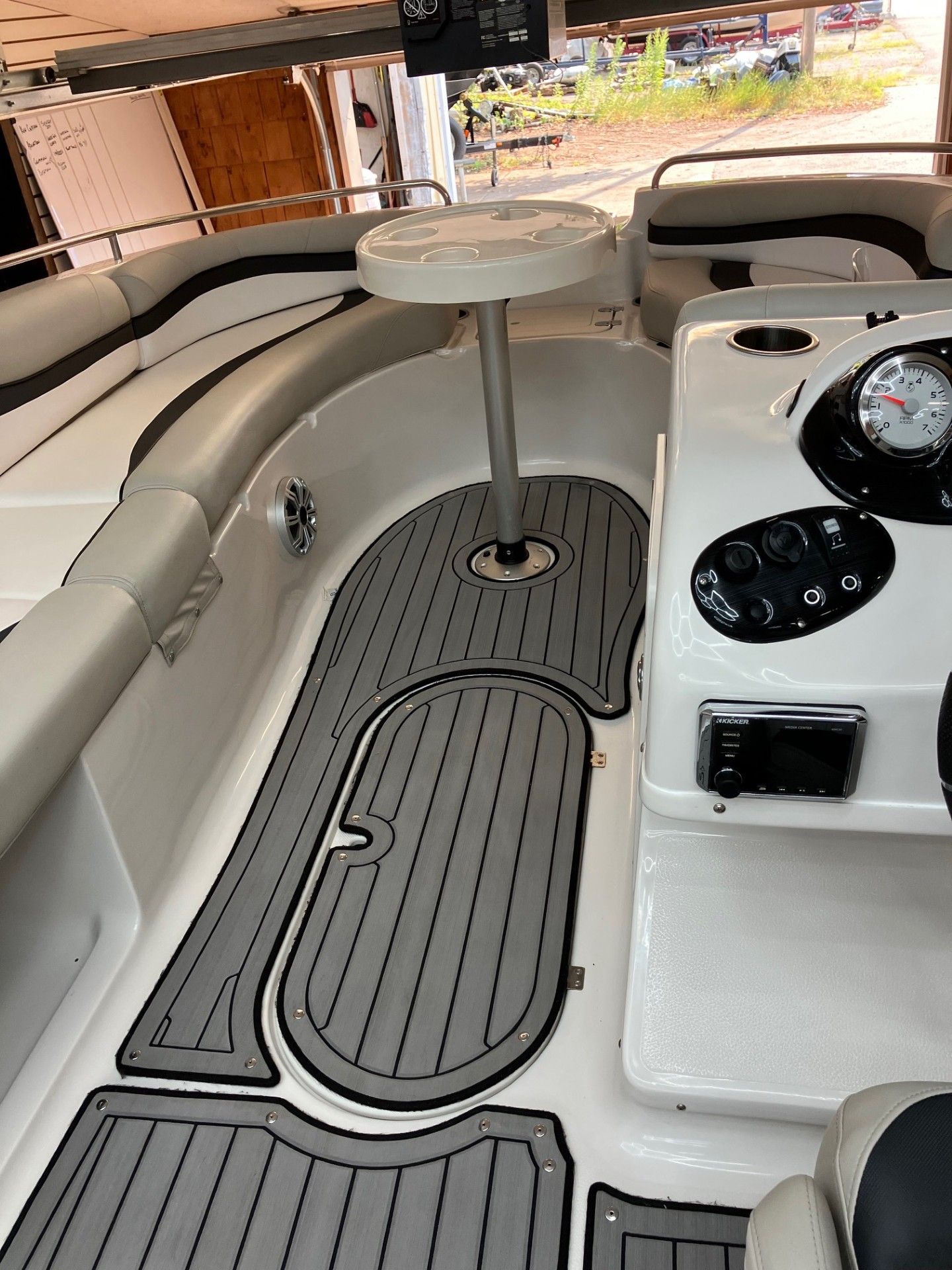 Boat cockpit seating area with gray cushioned bench seats, center table, and steering console.