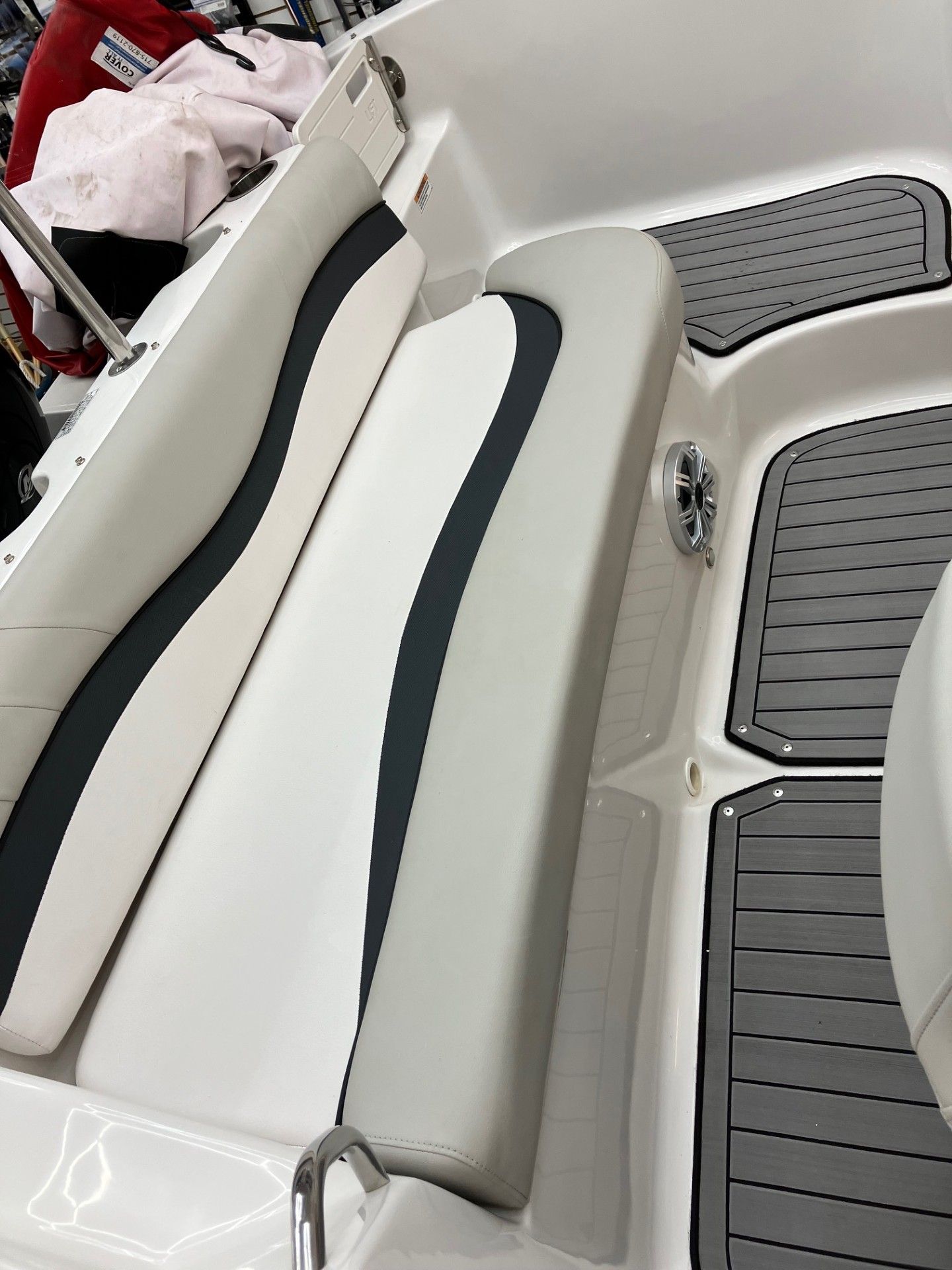 Boat seating area with white and gray upholstered benches and a gray deck mat