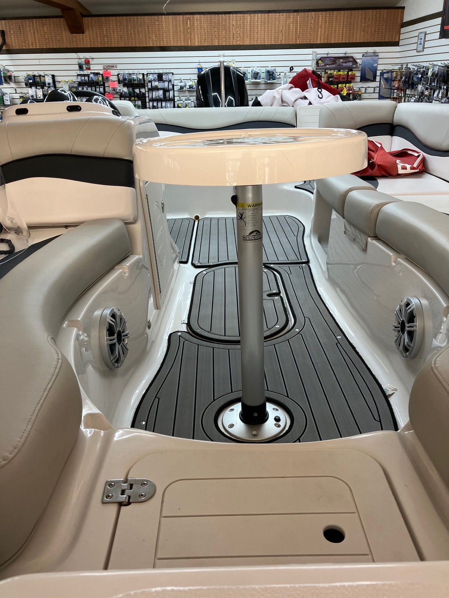Boat cabin with tan seating, a small round table, and gray deck flooring in a marina showroom.