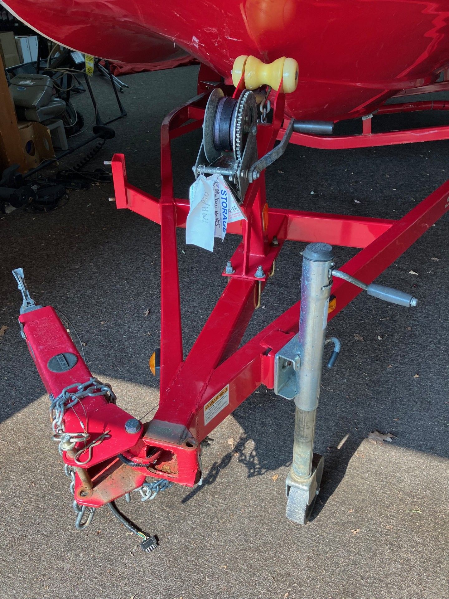 Red boat trailer with winch and support jack on a gravel surface