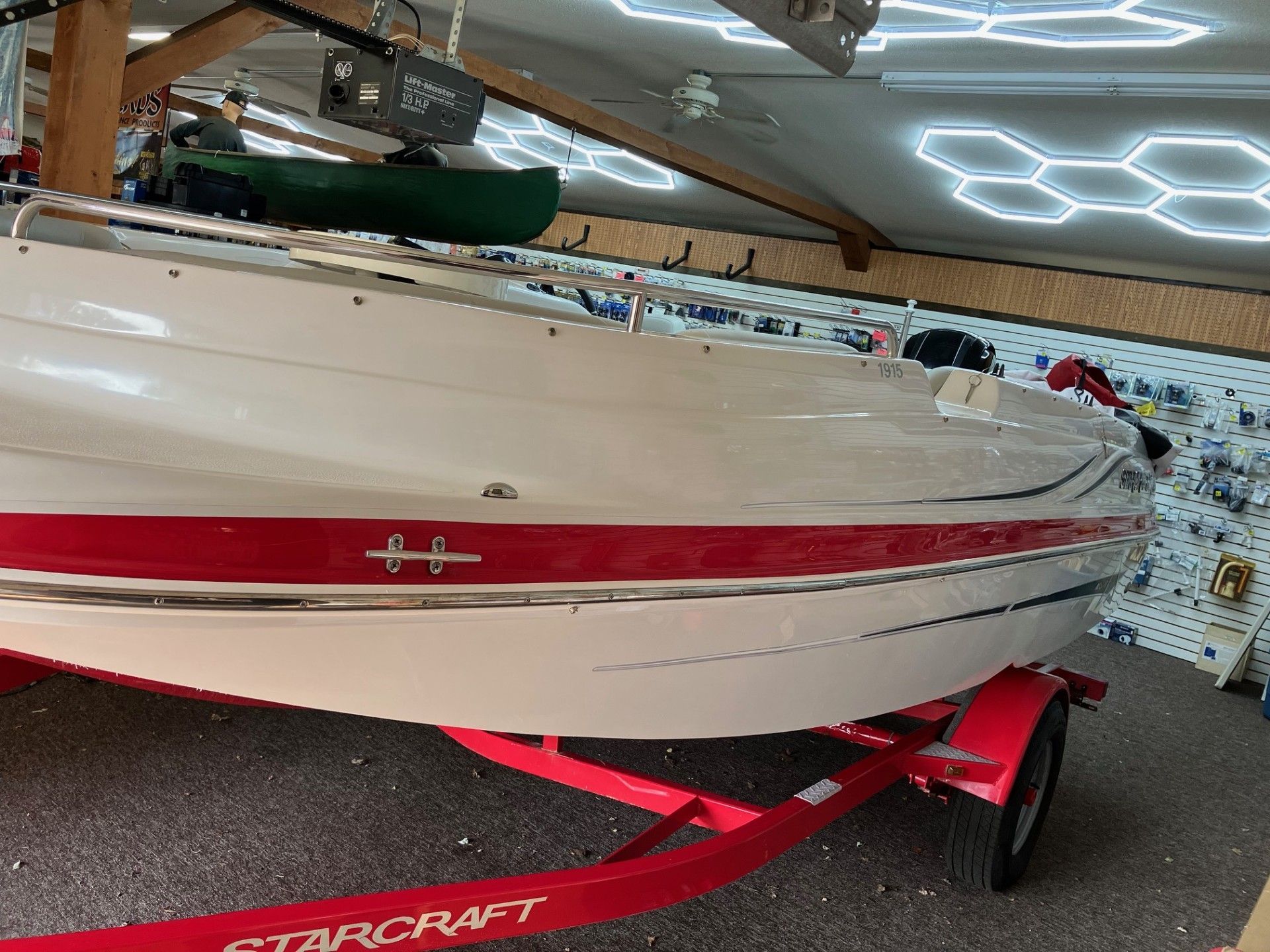 White speedboat on a red trailer inside a garage, with a mosaic wall in the background